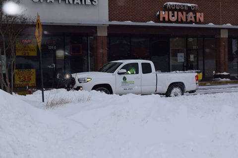 snow plow removes snow in commercial property lot