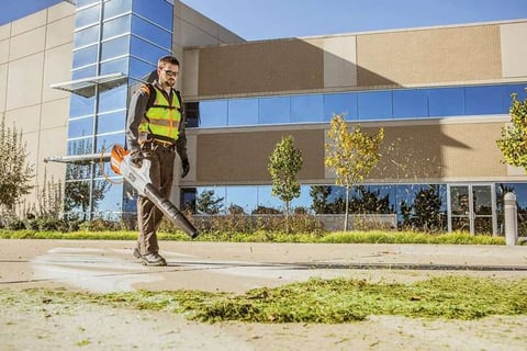 lawn care team uses electric blower to clear grass clippings